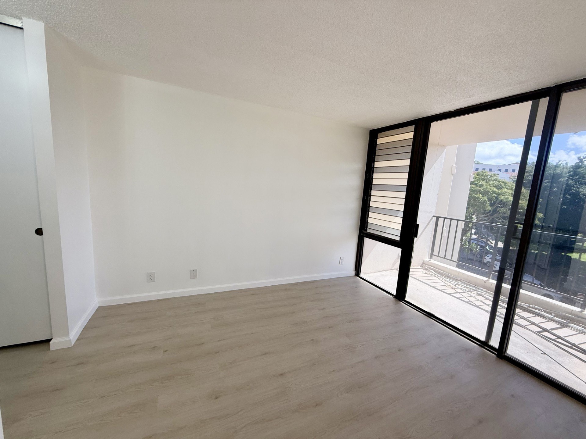 A room with wooden flooring and a sliding glass door.